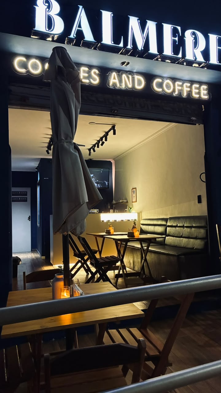 Fachada da Balmere à noite — letreiro iluminado, mesas e luz quente